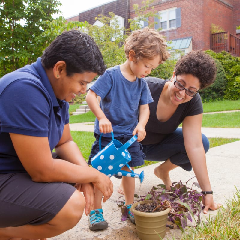Two mothers with their son, watering plants