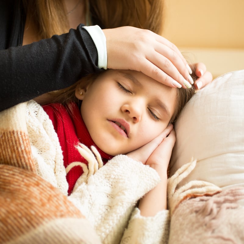 A mother holds the forehead of her sick child, checking for fever