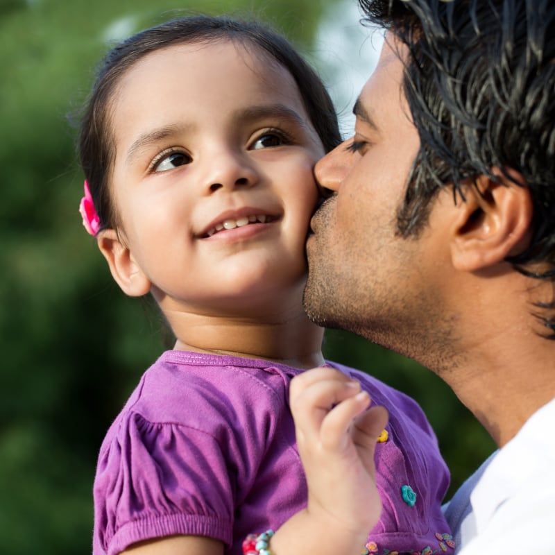 A South Asian father kisses is young daughter